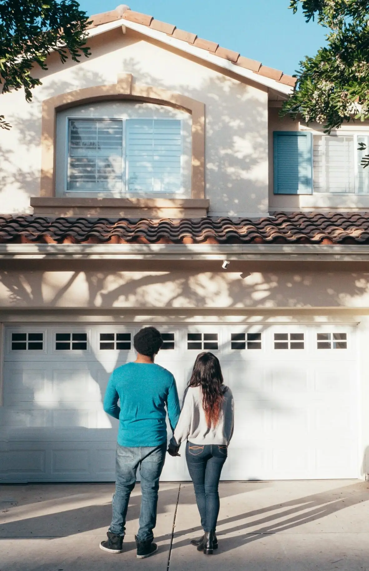A couple stands hand in hand, admiring their new house and life ahead.